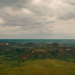 Vista aérea de paisagem do Cerrado em Tocantins, com áreas verdes extensas e formações rochosas.