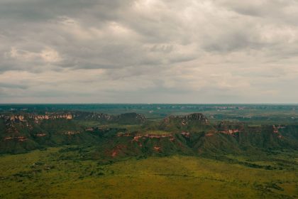 Vista aérea de paisagem do Cerrado em Tocantins, com áreas verdes extensas e formações rochosas.