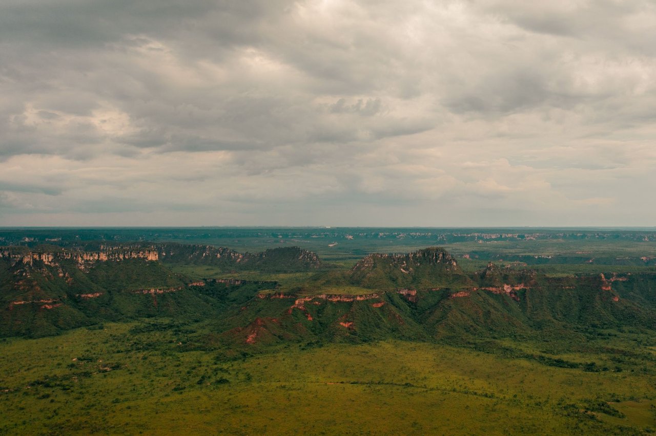 Vista aérea de paisagem do Cerrado em Tocantins, com áreas verdes extensas e formações rochosas.