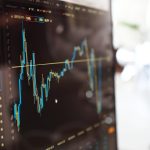 Tela de computador com gráficos financeiros e dados digitais.