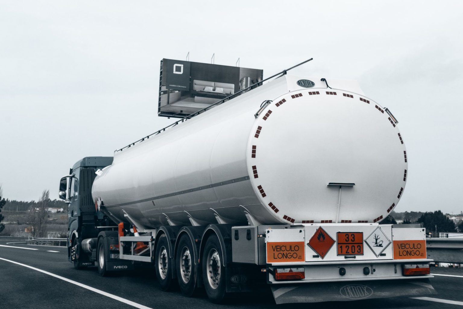 Caminhão-tanque visto por trás trafegando por uma rodovia para transportar combustível.