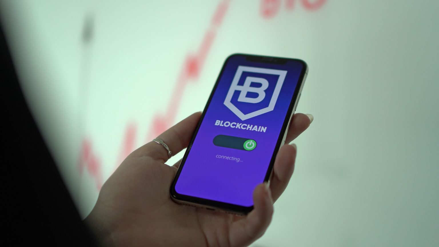 Mão segura um smartphone que exibe uma carteira digital de criptomoedas.