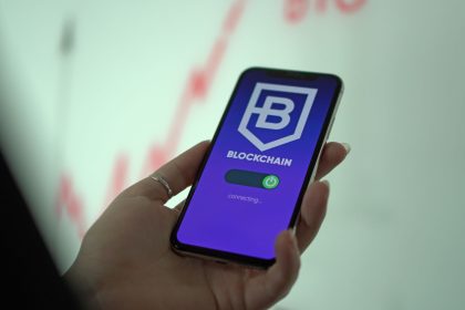 Mão segura um smartphone que exibe uma carteira digital de criptomoedas.