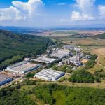 Vista de um parque industrial com fábricas e galpões em uma área próxima a uma cidade