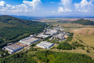 Vista de um parque industrial com fábricas e galpões em uma área próxima a uma cidade
